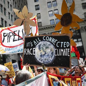 Image: Climate change activists carry signs as they march during a protest in downtown in Philadelphia a day before the start of the Democratic National Convention on July 24, 2016.